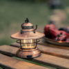 Barebones Edison Mini Lantern Copper on a wood table in a campground